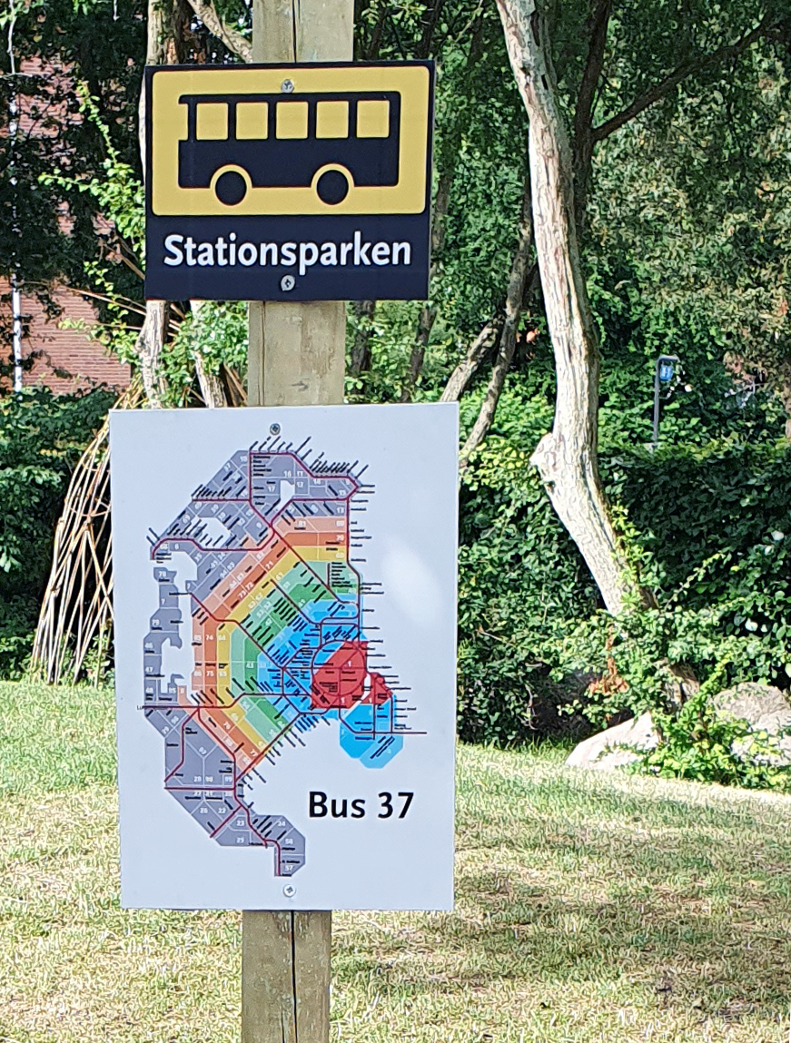 Børnehuset Stationsparkens nye fine busskilte. Øverst er et lille billede med et busikon. Nederst er et større billede, der illustrerer Storkøbenshavns buszoner